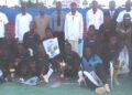 Les joueurs d’OURAGAN FC posant avec leur trophée devant le parterre de personnalités